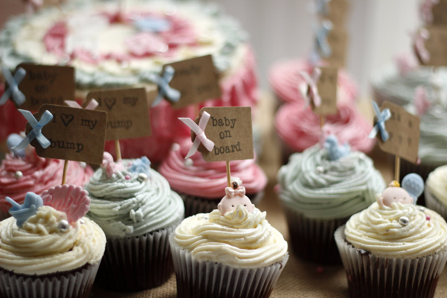 Tri-colored cupcakes featuring personalized cupcake toppers that say "baby on board, and "i heart my bump"