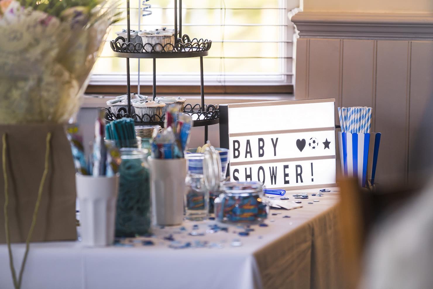 Personalized baby shower sign featuring a table filled with blue confetti and party favors