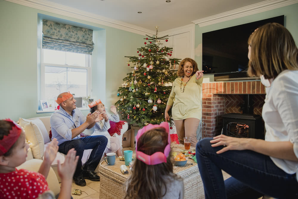Family of six playing a game of charades in their living room on christmas day