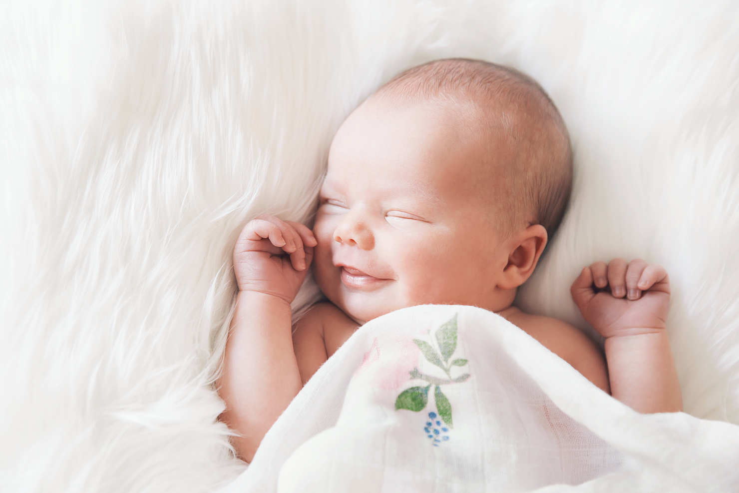 Dreaming infant sleeping on a white fuzzy blanket