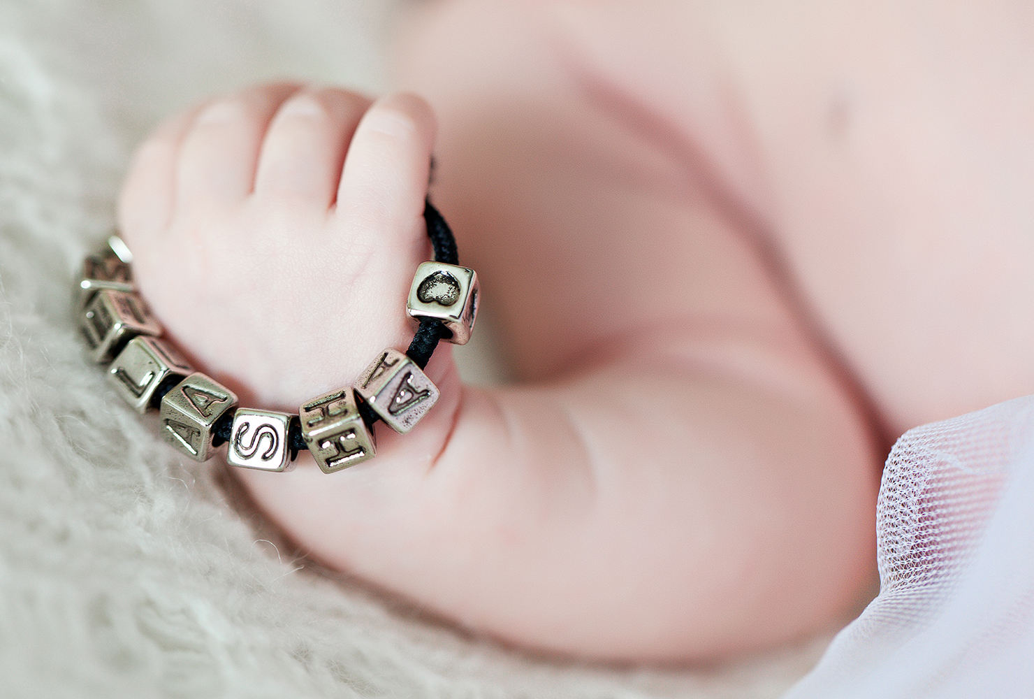 baby holding a bracelet with their name.