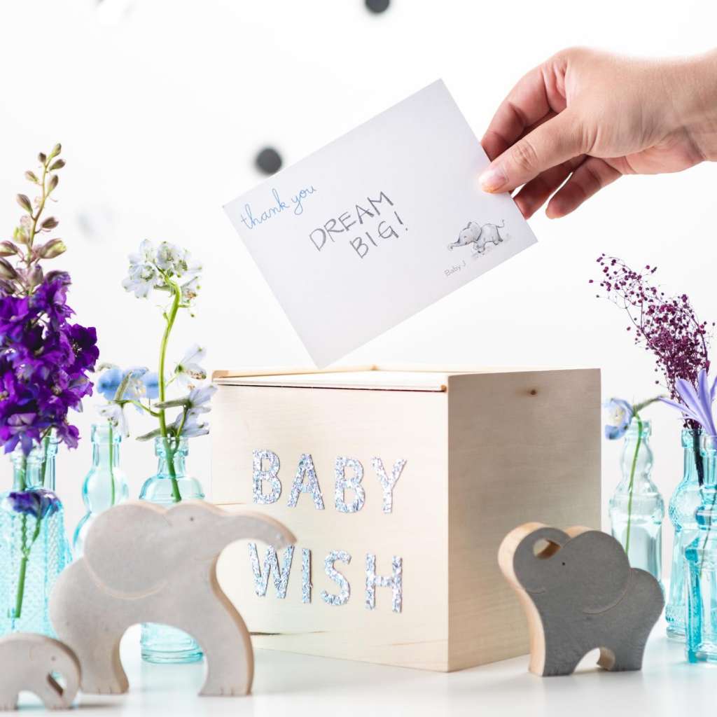 someone dropping wishes for the baby into a baby wish wooden box.